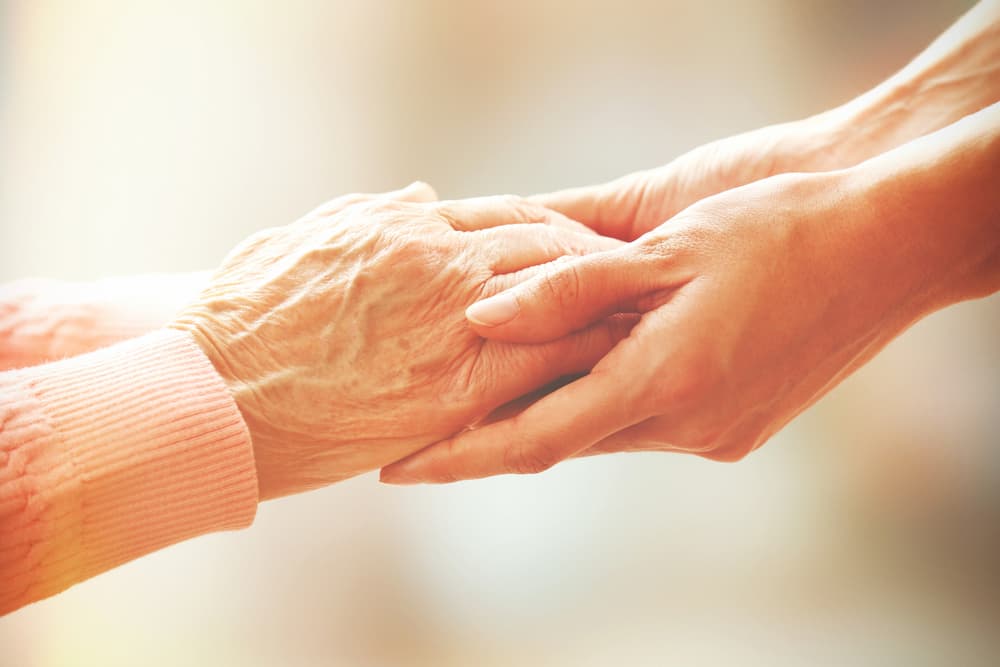 Female elderly hands holding younger female hands