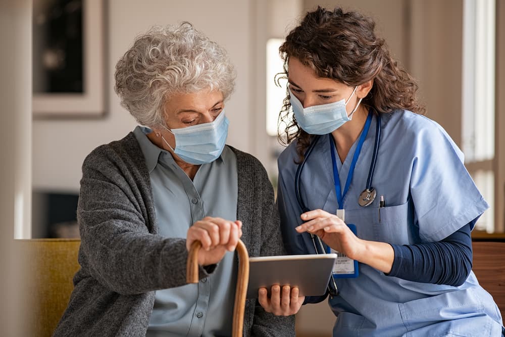Nurse and elderly woman with masks on selecting medication management options