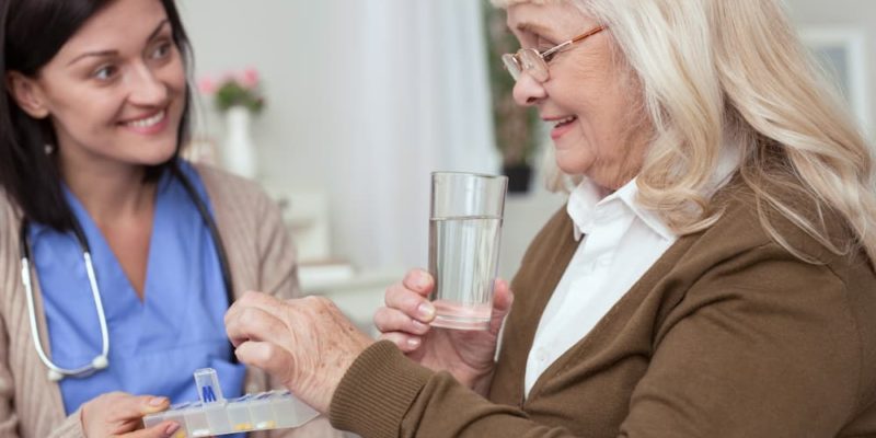 Nurse giving elderly woman her daily medication