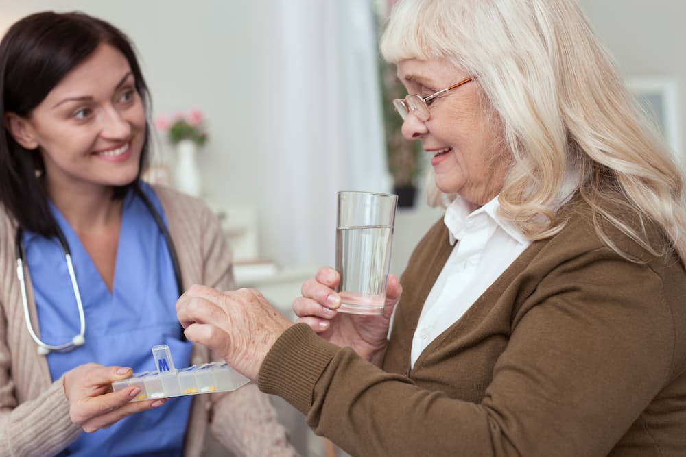 Nurse giving elderly woman her daily medication