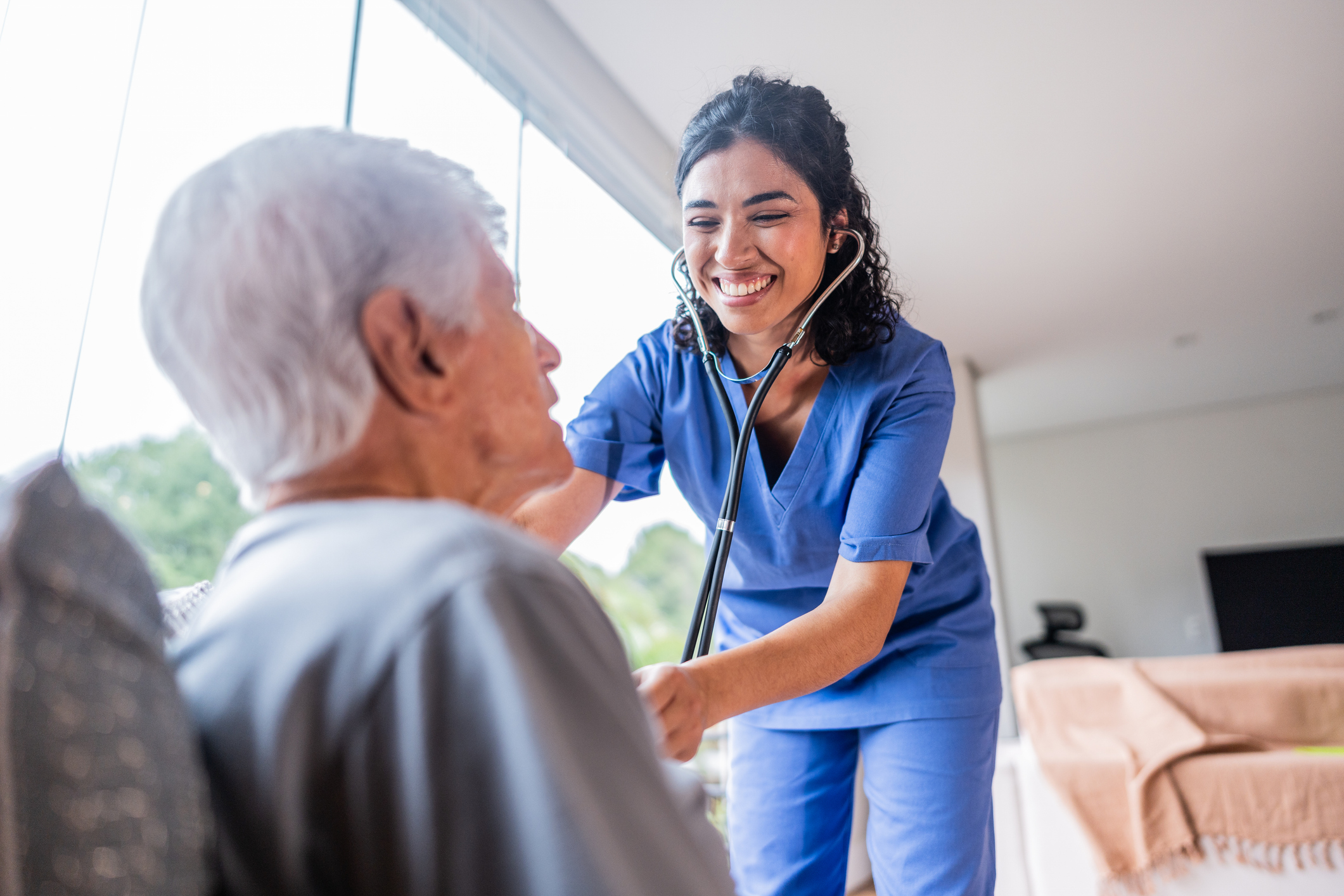 Healthcare provider examining a senior man at home