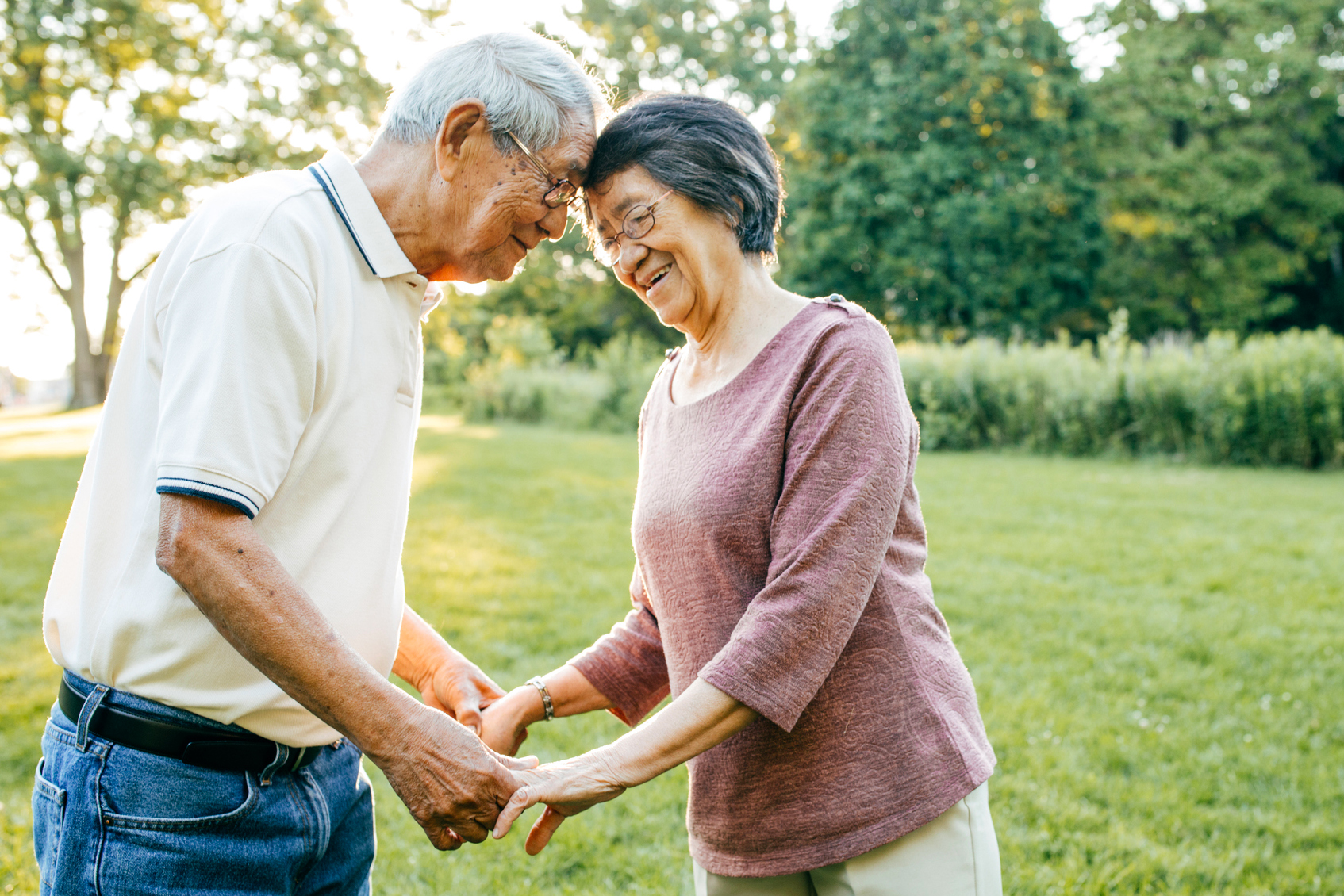 Senior asian couple holding hands and touching foreheads